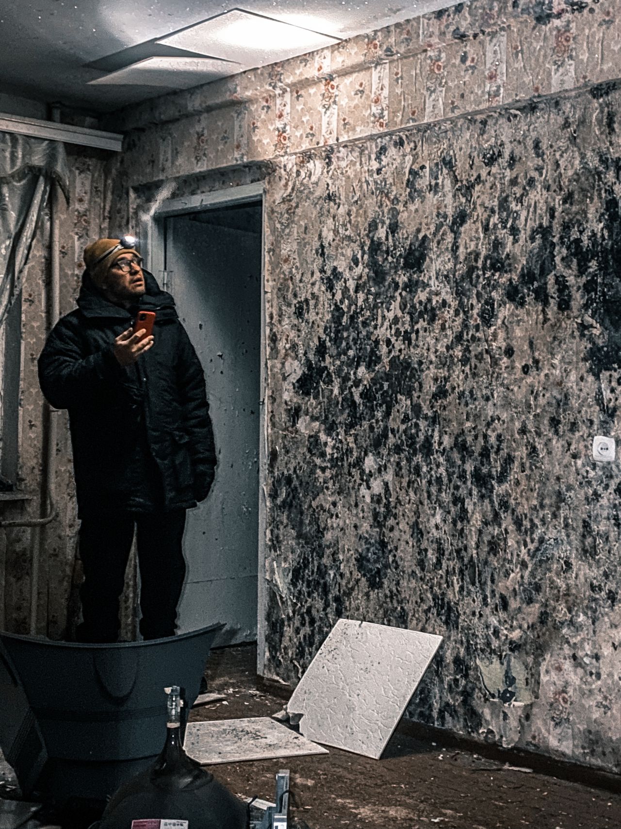 Specialist inspecting a wall heavily covered in mold before remediation
